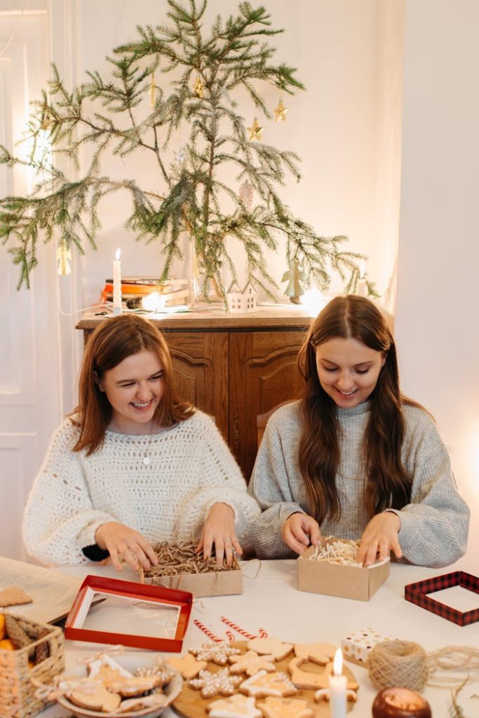 young-girls-boxing-cookies-for-holidays-5623629 Two women enjoying a cozy indoor holiday celebration with Christmas cookies and gifts.